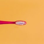 pink and yellow toothbrush on orange background