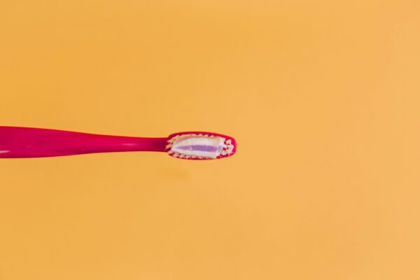 pink and yellow toothbrush on orange background