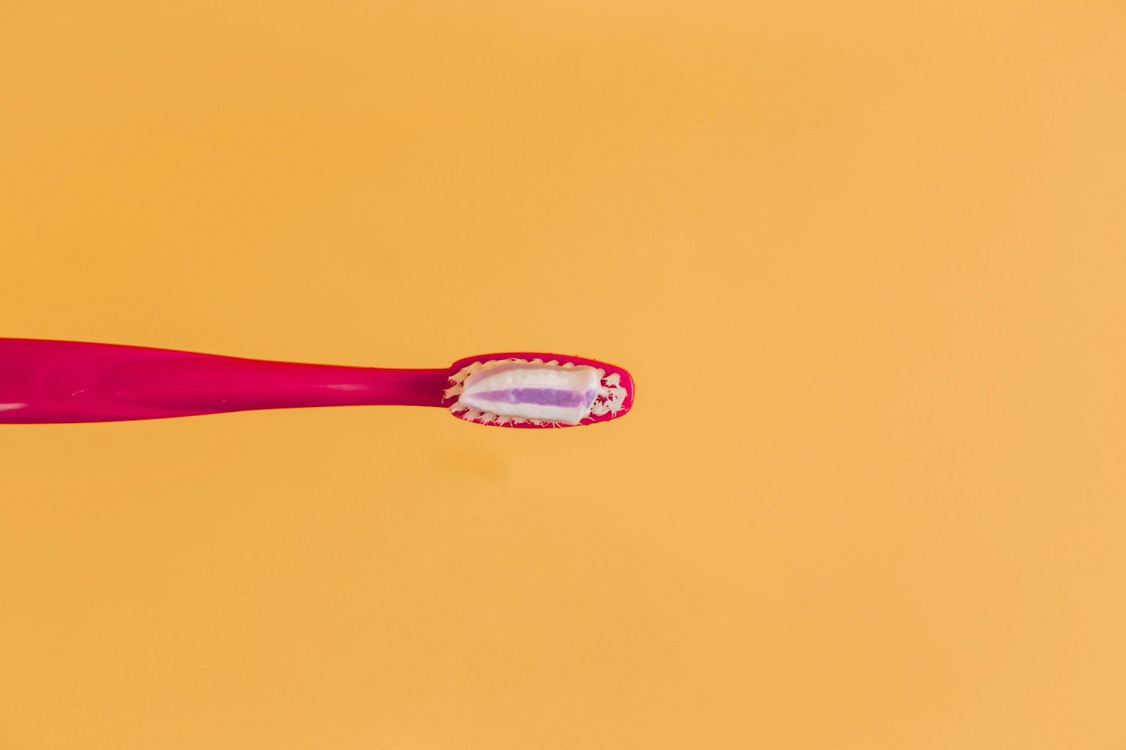 pink and yellow toothbrush on orange background