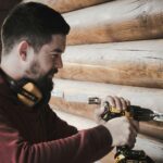 man in red long sleeve shirt holding black and yellow corded headphones