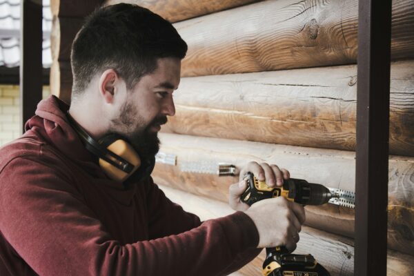 man in red long sleeve shirt holding black and yellow corded headphones